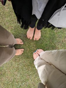 Barefeet of three people walking on the grass