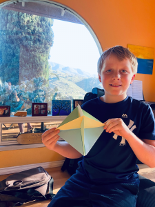 Picture of boy holding up a piece of origami that he created for Project VisMO.