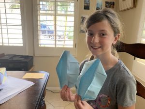 Picture of girl holding up a piece of origami that she created for Project VisMO.